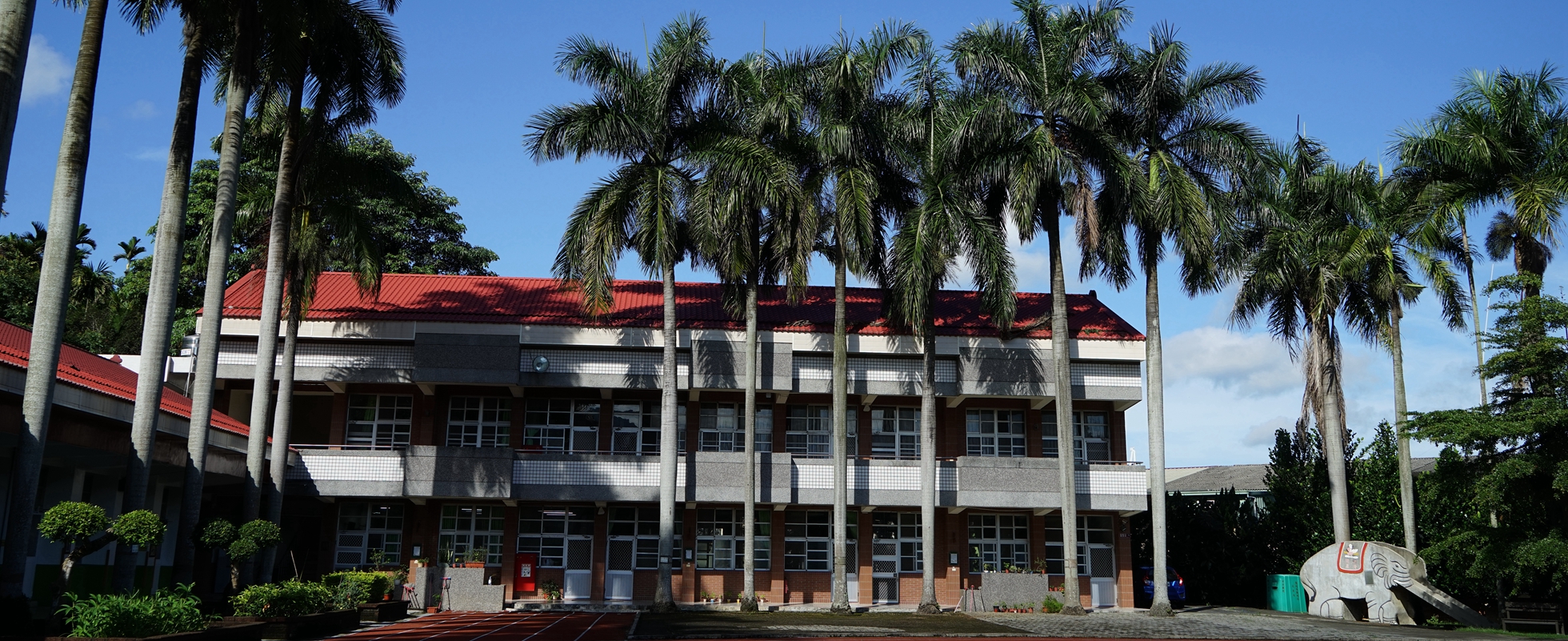 學校西邊大樓。為二層樓建築，上覆紅色屋瓦，前有一排大王椰子樹